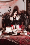 Halloweenská výzdoba se ženou držící balonek netopýra nad strašidelným stolem