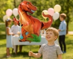 Dítě s fóliovým balónkem dinosaurus T-Rex na oslavě