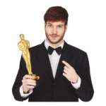 Muž v obleku drží zlatou filmovou trofej při slavnostním večeru